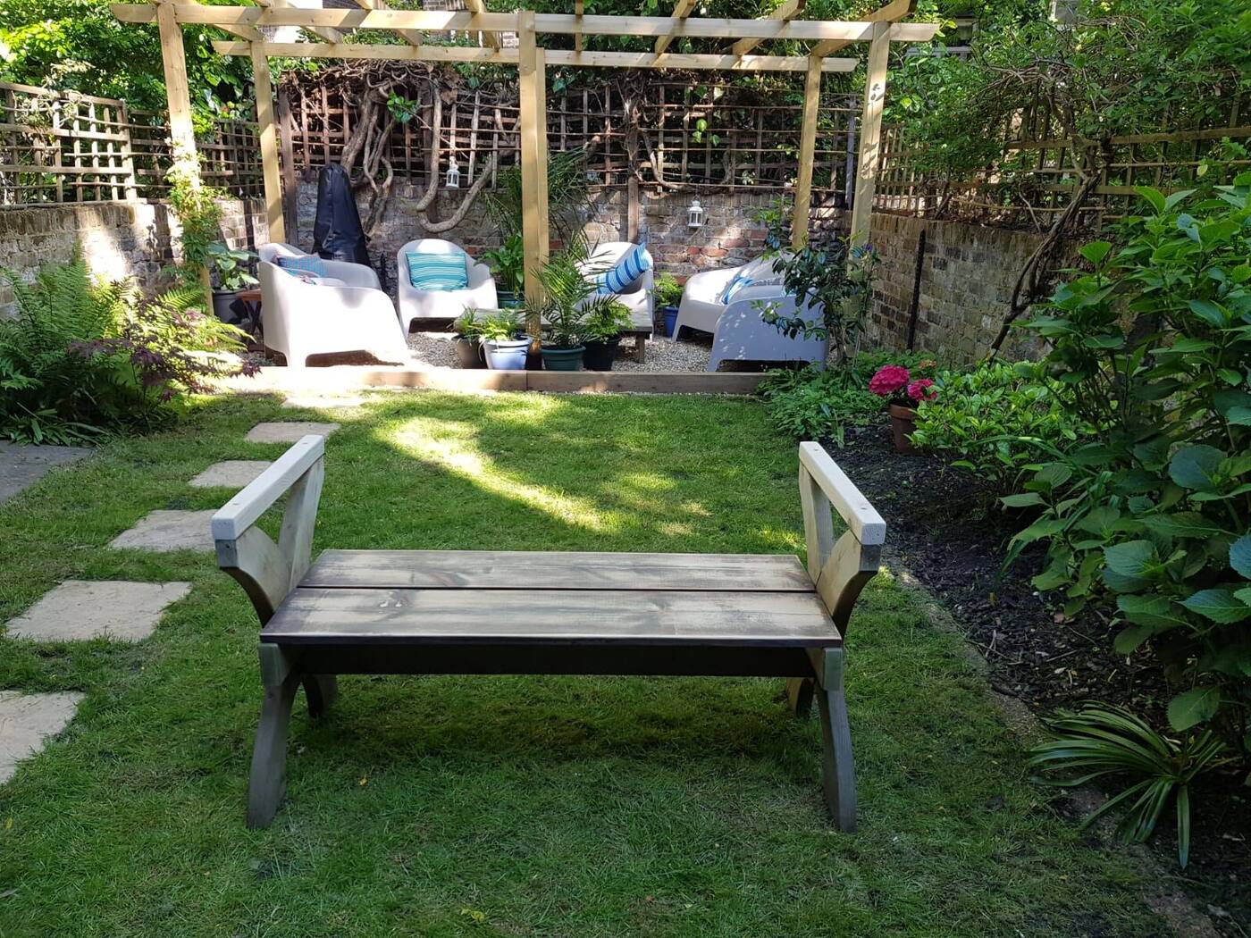 London garden with timber pergola, soft seating and lush planting