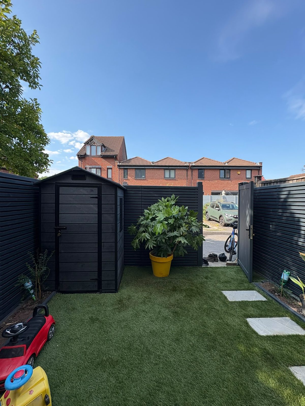 Black slatted garden fencing and artificial lawn with storage shed, Rotherhithe SE16