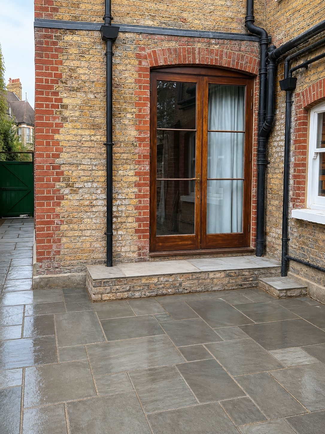 Grey sandstone patio meeting timber French doors on a London period house